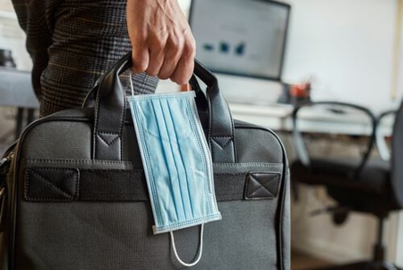 close up of man carrying briefcase and mask back into office